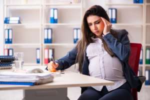 Mujer embarazada joven que trabaja en la oficina - abogado laboral